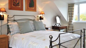 Ein Schlafzimmer mit einem Bett, zwei Wandlampen, einer Holzkommode, einem Spiegel und zwei gerahmten Kunstwerken.
