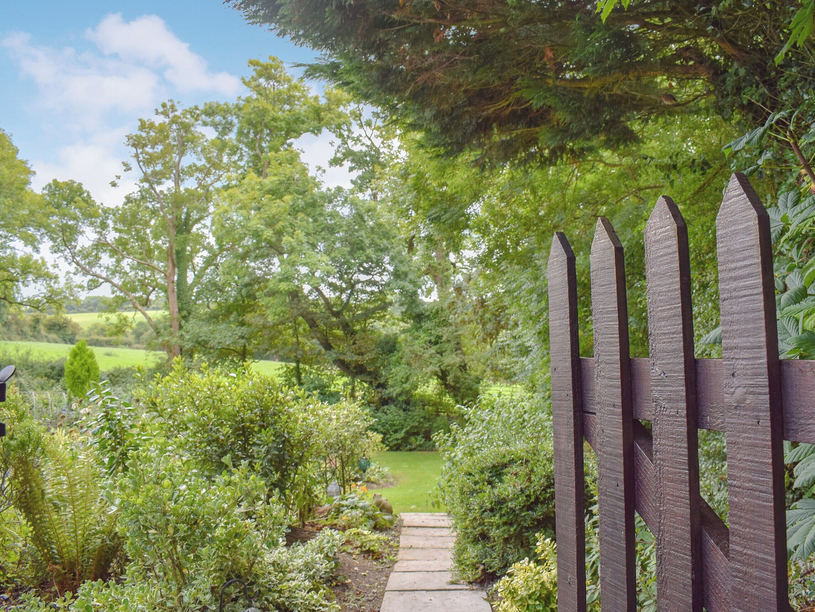 A wooden gate leading into a lush garden with a stone pathway.