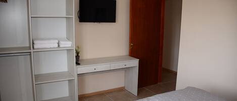 Een slaapkamer met een bed, een bureau, een kledingkast en een televisie.