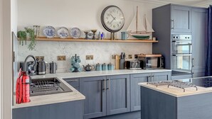 Una cocina moderna con armarios grises, una isla central, un reloj y una estufa.