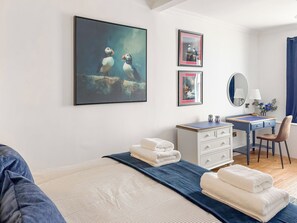 A bedroom with a bed, a desk, a chair, a dresser, and artwork on the walls. - 4 bedroom accommodation in Cellardyke, near Anstruther (Cellardyke, near Anstruther)