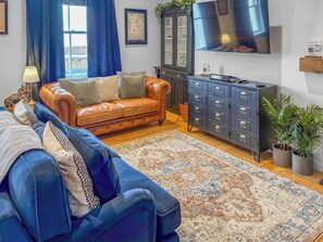 A living room with a leather sofa, a blue sofa, a patterned rug, a cabinet, and a TV.
