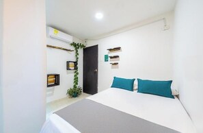 Relax in a serene space with a large bed, potted plant, and wall-mounted shelf.