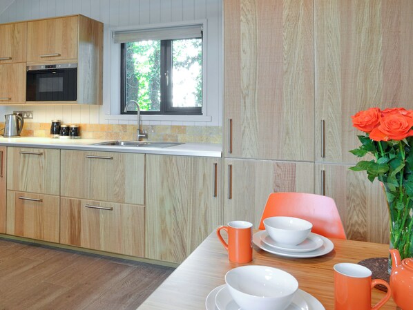 A modern kitchen with wooden cabinets, a built-in oven, and a window.