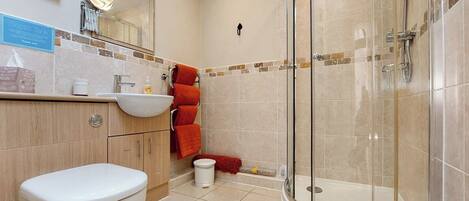 A bathroom with a toilet, sink, and glass-enclosed shower.