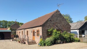 A stone building with a sloped roof, a wooden door, and a small porch with steps leading up to it. - 1 bedroom accommodation in Wansford, near Driffield (Wansford, near Driffield)
