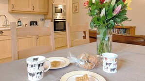 A dining table with plates, a mug, and a vase with flowers. - 1 bedroom accommodation in Wansford, near Driffield (Wansford, near Driffield)
