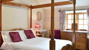 A four-poster bed with a wooden headboard, a bedside table with a lamp, a dresser, and a mirror on the wall. - Brothersfield Cottage (Hartsop, near Patterdale)