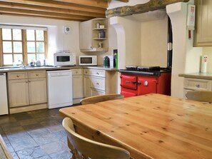 A kitchen with white cabinets, a red stove, a wooden table, and a window.