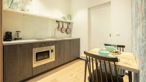 Una cocina moderna con horno empotrado, una mesa de comedor con sillas y un colgador para ollas.