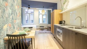 Cocina compacta con comedor, muebles de madera y ventana que aporta luz natural.