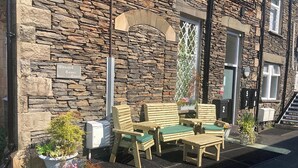 A stone building with a sign reading "Wansfell Tower Court." There are wooden outdoor seating arrangements and potted plants. - 1 bedroom accommodation in Ambleside (Ambleside)