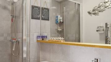 A modern bathroom with a shower, toilet, and sink. There are two signs on the wall with bathroom rules.