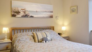 A bedroom with a bed, two bedside tables, a nightstand, a wall-mounted lamp, a framed picture, and a decorative heart on the wall. - 1 bedroom accommodation in Ambleside (Ambleside)