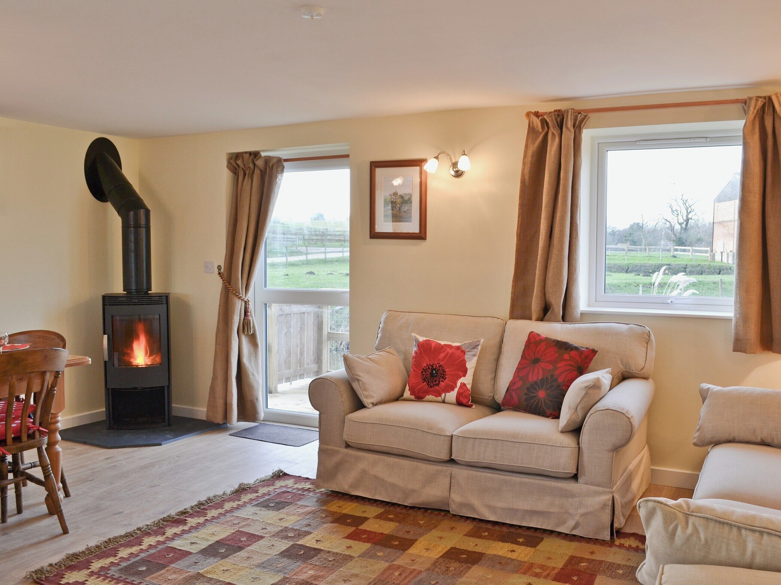 A living room with a sofa, a wooden chair, a patterned rug, a fireplace, and a view through a window.