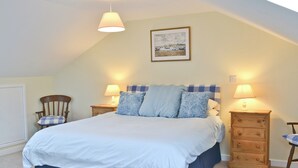 A bedroom with a bed, two bedside tables, a chair, and a painting on the wall. - 4 bedroom accommodation in Rye Foreign, Rye (Rye Foreign, Rye)