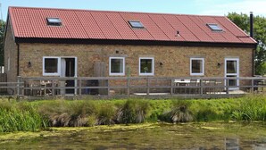 A brick building with a red roof, multiple windows, and a wooden deck in front. - 4 bedroom accommodation in Rye Foreign, Rye (Rye Foreign, Rye)