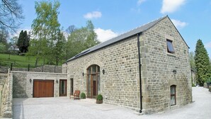 Een stenen gebouw met een grote garagepoort, een houten bankje en een verharde oprit.