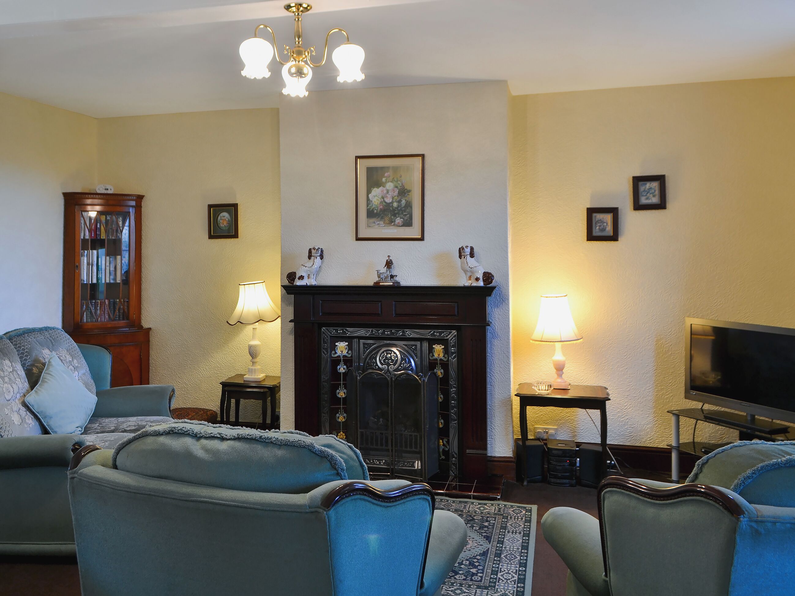 A living room with a fireplace, two armchairs, a sofa, a television, and a bookshelf.