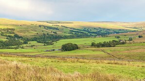 Un paysage rural caractérisé par des collines douces, des maisons dispersées et des murs de pierre.