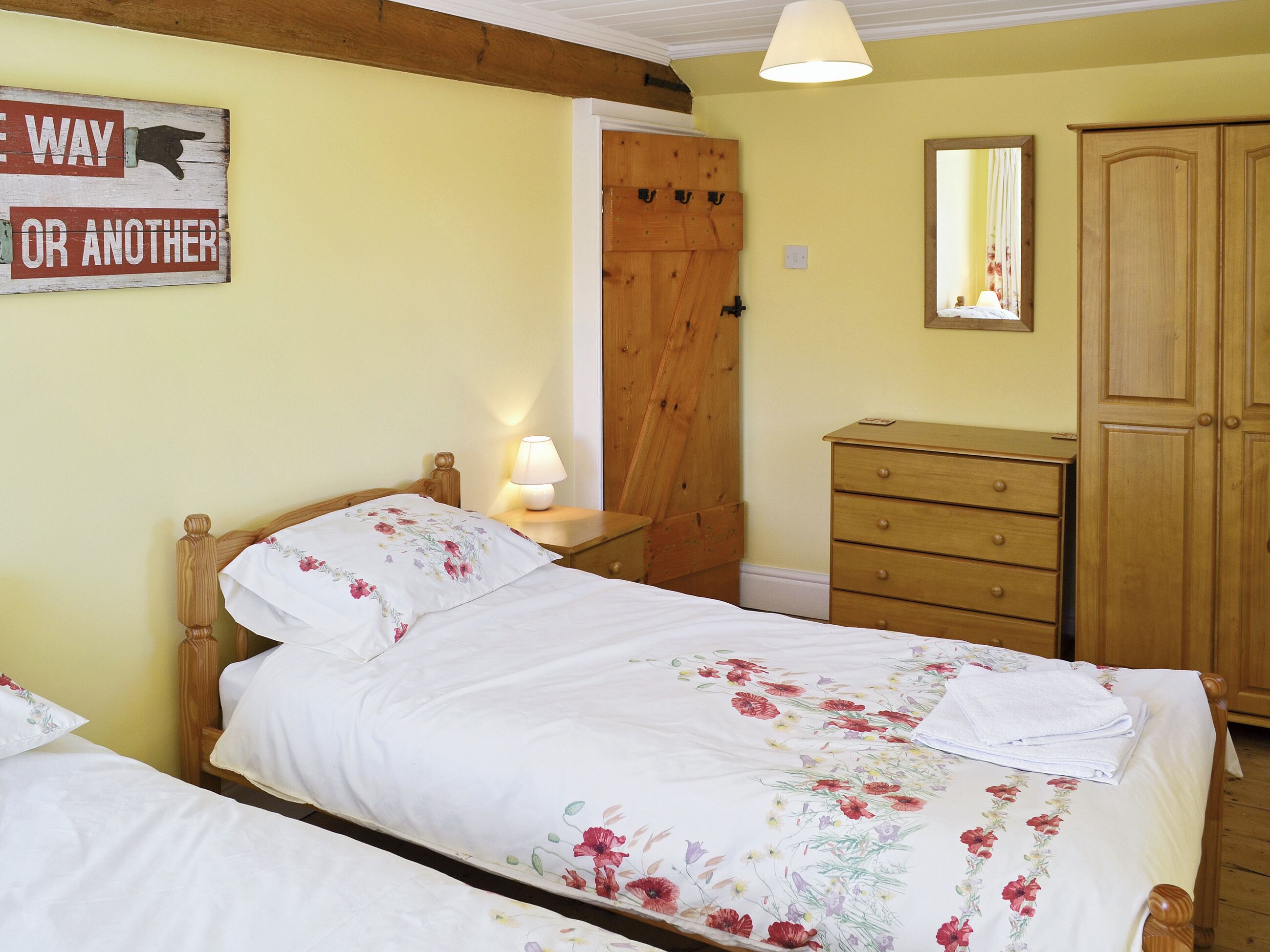 Une chambre à coucher avec un lit, une table de chevet, une commode et un miroir.