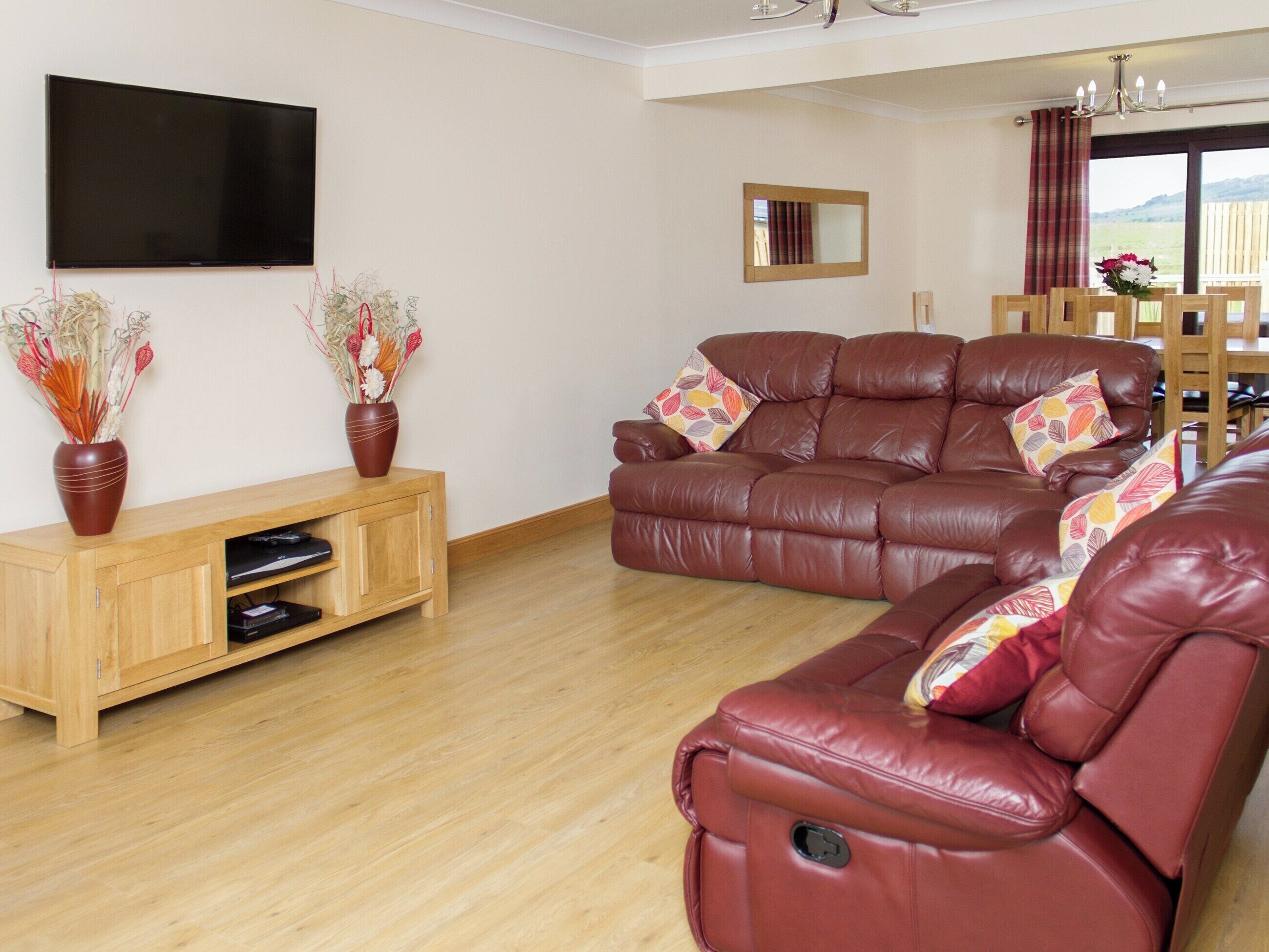 Een woonkamer met een leren bank, een houten tv-meubel en een flatscreen tv aan de muur.