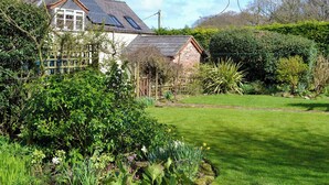 Une maison avec un jardin, une clôture en bois et des panneaux solaires sur le toit.