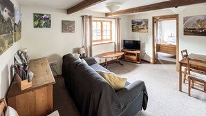 A cozy living room with a sofa, TV, wooden furniture, and artwork on the walls. - 1 bedroom accommodation in North Newton (North Newton)
