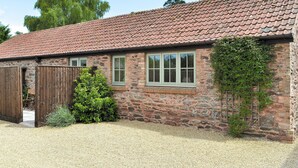 A stone building with a tiled roof, a wooden door, and a window with shutters. - 1 bedroom accommodation in North Newton (North Newton)