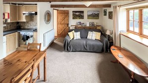 A cozy, open-plan living space with a kitchen, dining area, and a sofa with cushions. - 1 bedroom accommodation in North Newton (North Newton)