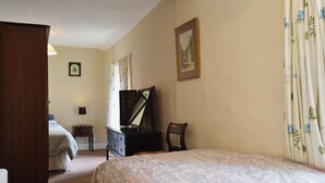 Une chambre à coucher comprenant un lit, une commode, une chaise, un bureau et un miroir.
