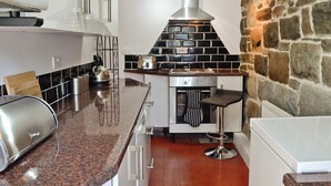 A modern kitchen with a stone accent wall, a built-in oven, and a stainless steel toaster. - 2 bedroom accommodation in Trefor, near Caernarfon (Trefor, near Caernarfon)