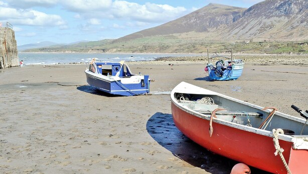 A beach with three boats, one red and two blue, anchored on the sand. - 2 bedroom accommodation in Trefor, near Caernarfon (Trefor, near Caernarfon)