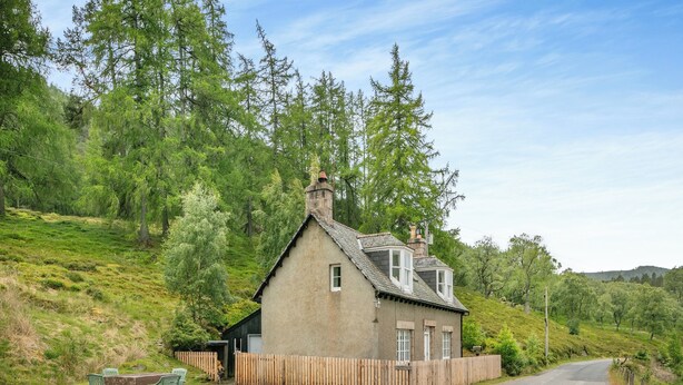 Une maison de plain-pied avec un toit en pente, une cheminée et un petit porche.