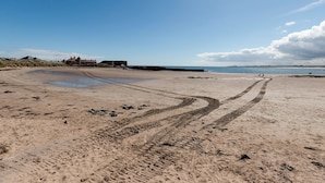 Une plage de sable avec des empreintes et un bâtiment visible au loin.