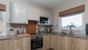 Une cuisine moderne avec des meubles en bois, un four encastré, un four à micro-ondes et une grande fenêtre offrant une belle vue.