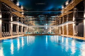 Piscina interior com design moderno, com área de mergulho central e várias pistas.