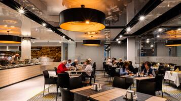 En moderne restaurant med forskellige siddepladser, herunder borde og stole, samt et buffetområde.