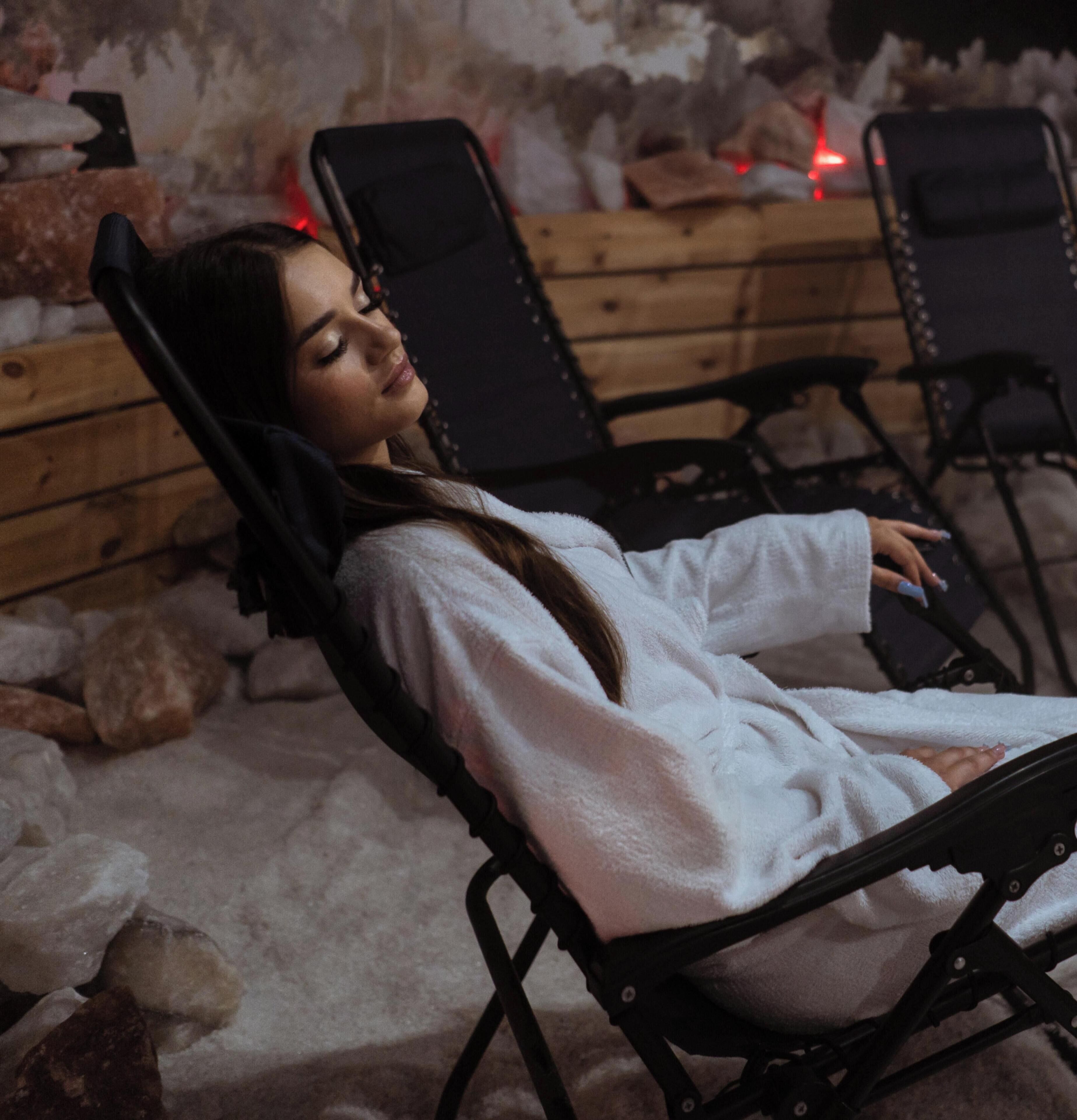 A person lying in a reclining chair in a room with a rustic stone wall and wooden furniture.