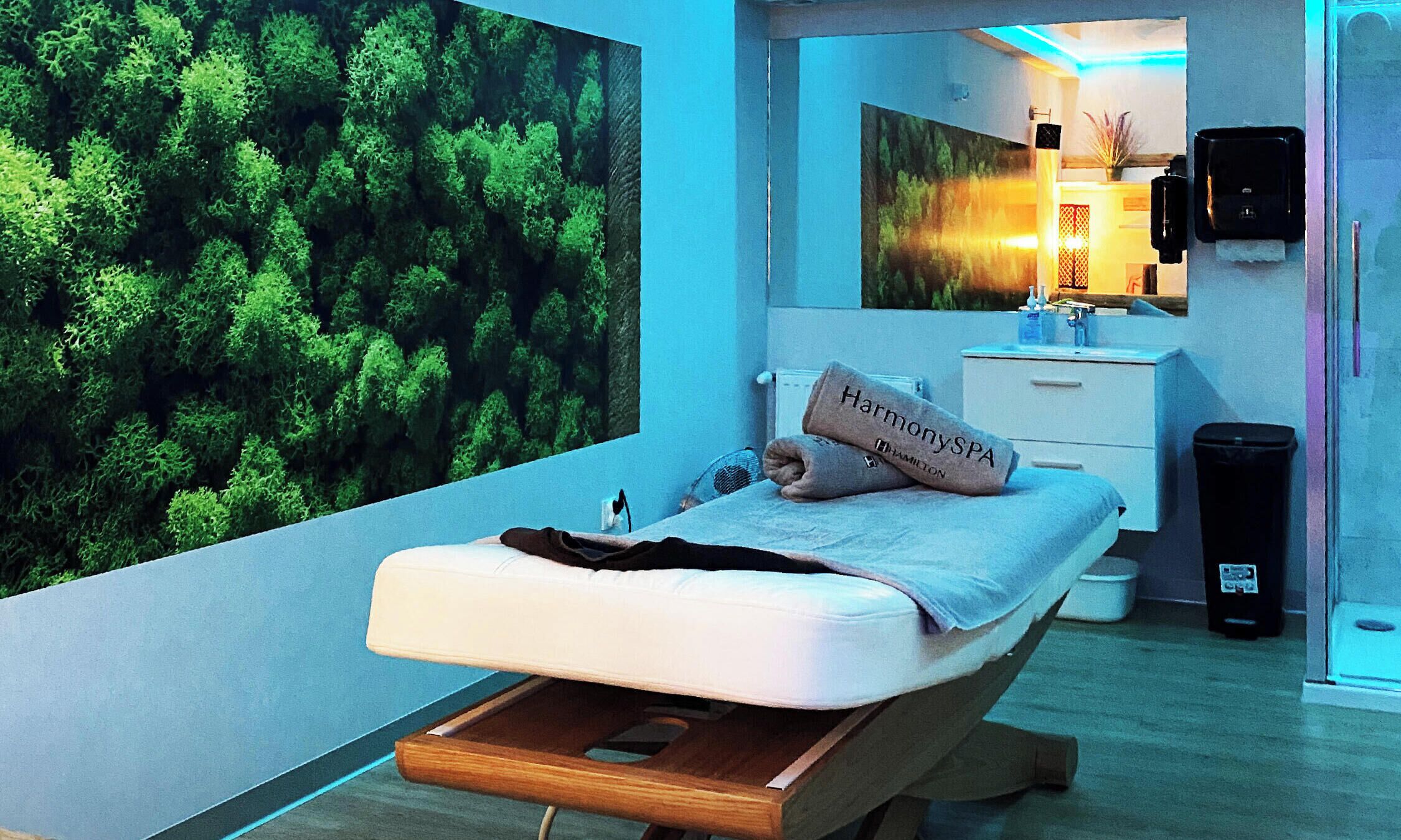 Un dormitorio moderno con cama, mesita de noche, espejo, calentador de pared y cubo de basura.