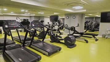 Ein Fitnessraum mit Laufbändern, Crosstrainern und Krafttrainingsgeräten.