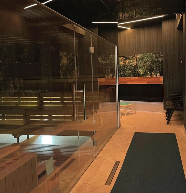 Um interior moderno com divisória de vidro, bancos de madeira, uma pequena mesa e vista para árvores através do vidro.