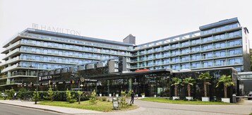 A modern hotel with multiple floors, a glass facade, and a prominent entrance.