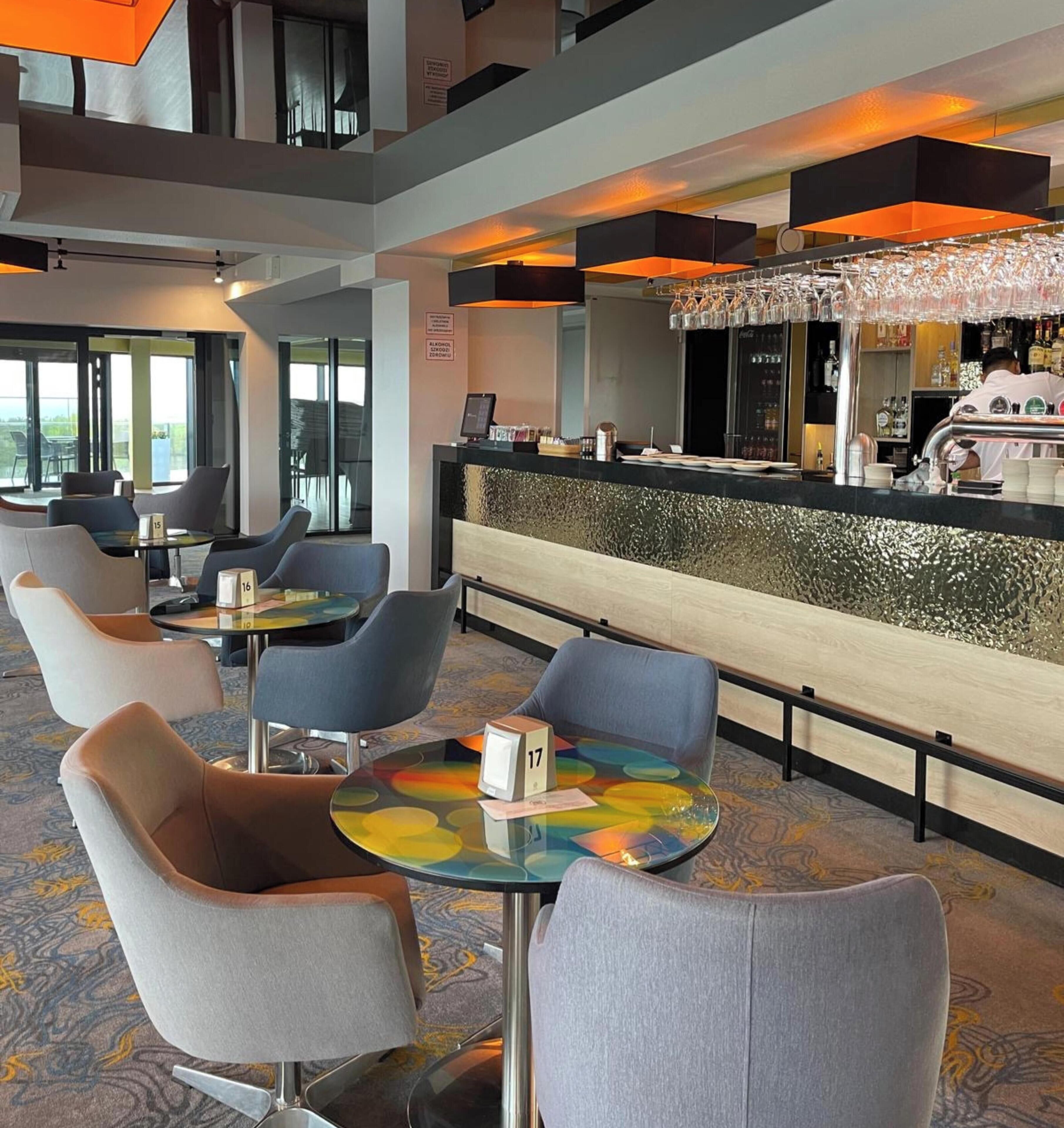 A hotel lobby with a bar area, seating arrangements, and a view through the glass doors.