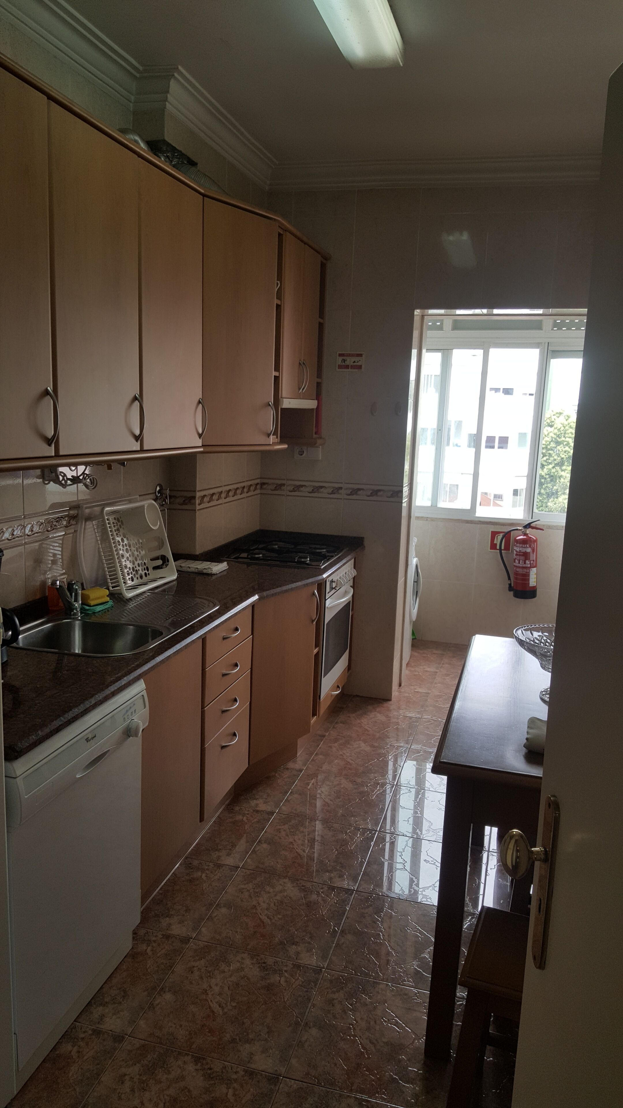 A kitchen with wooden cabinets, a stove, a dishwasher, and a window providing natural light.