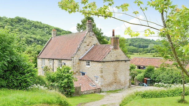 A stone house with a red-tiled roof, surrounded by lush greenery and a clear sky. - 3 bedroom accommodation in Rievaulx, near Helmsley (Rievaulx, near Helmsley)