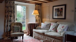 A cozy room with a floral-patterned armchair, a sofa with floral cushions, a patterned rug, and a lamp on a small table. - 3 bedroom accommodation in Rievaulx, near Helmsley (Rievaulx, near Helmsley)