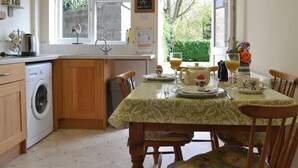 Una cocina con lavadora, una mesa de comedor con sillas y un ventanal con vista a zonas verdes.