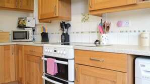 Una cocina con armarios de madera, microondas, estufa y lavavajillas.