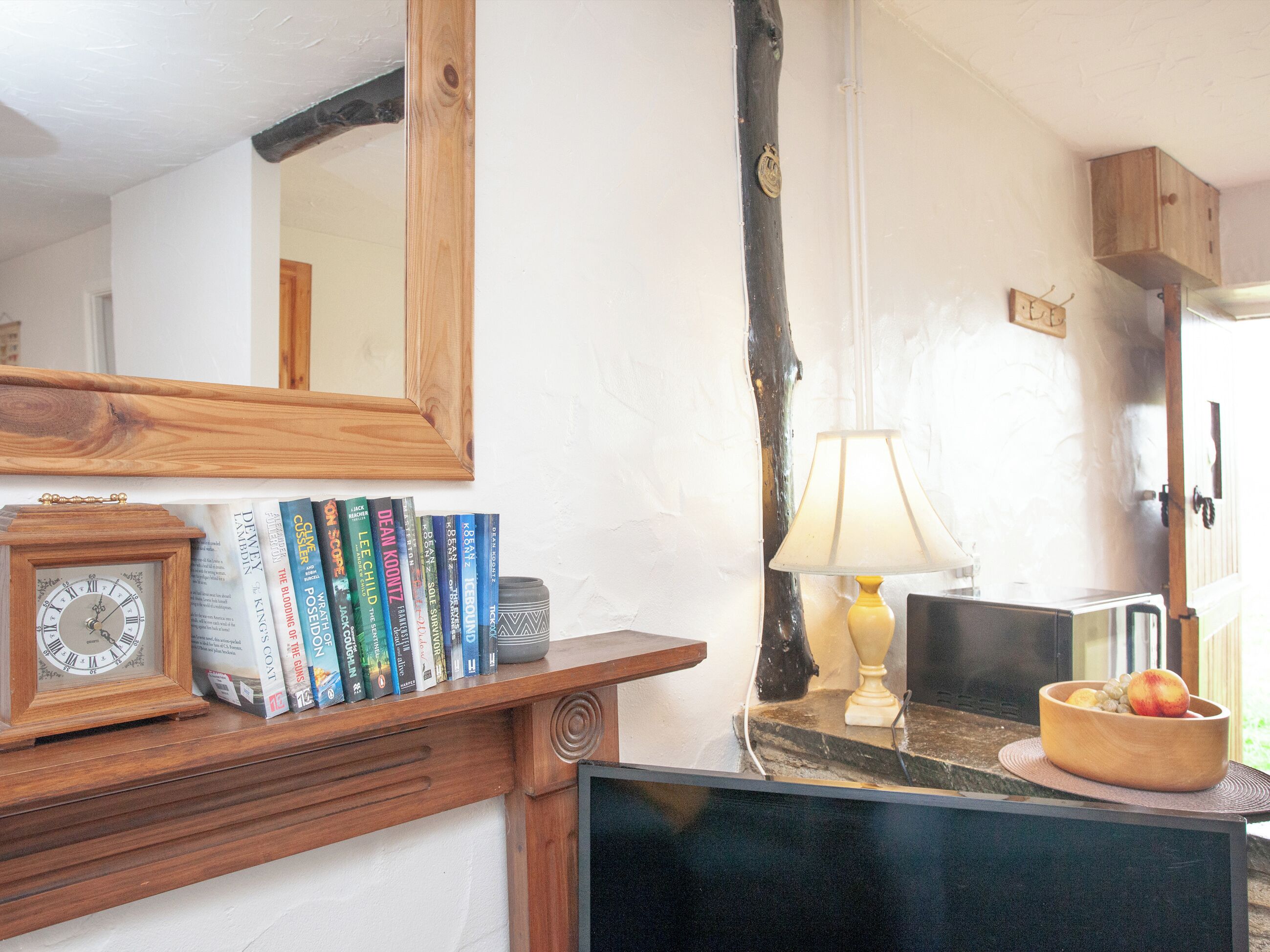Une pièce avec une étagère en bois où sont posés des livres, une horloge et une lampe.
